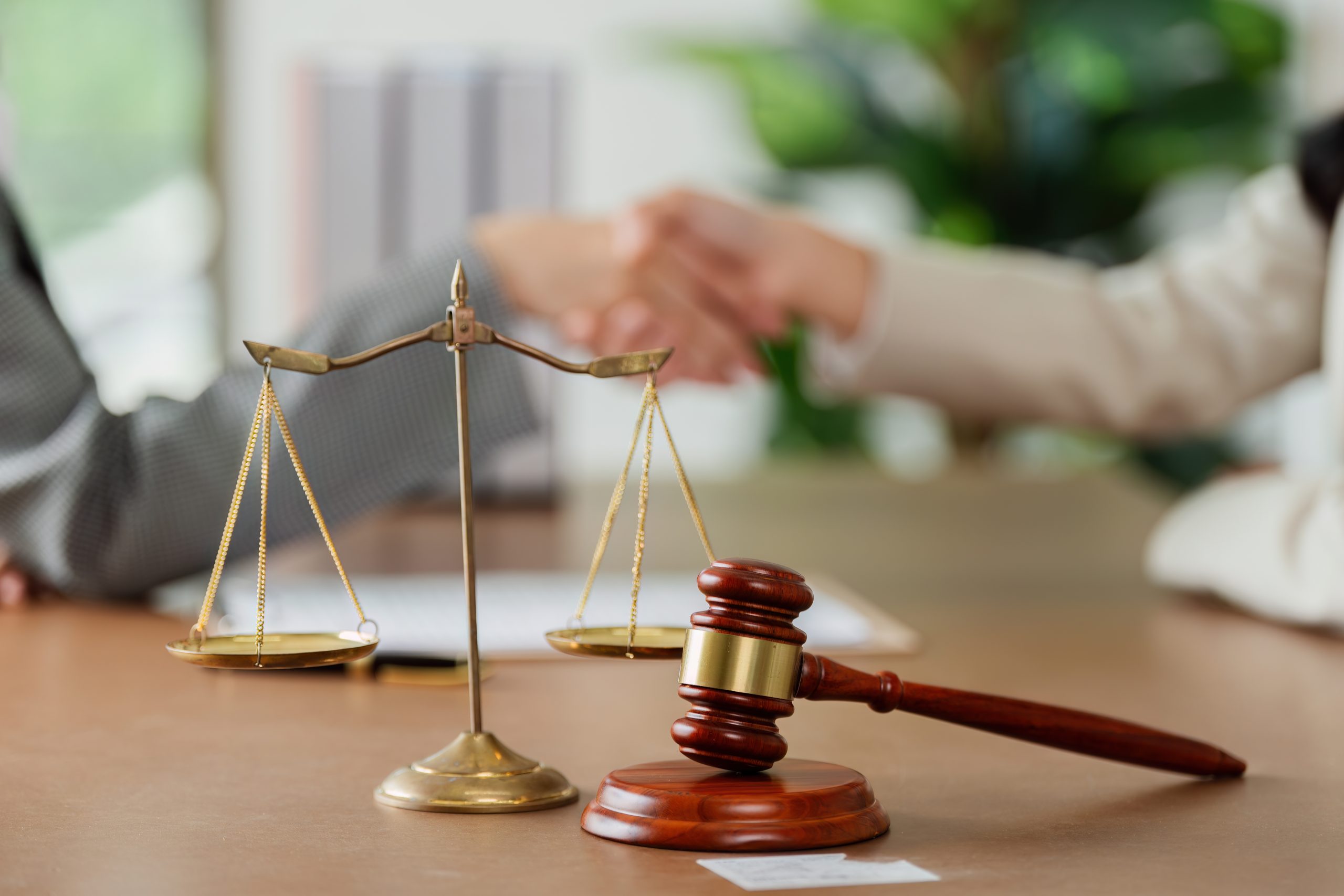people shaking hands behind a mallet and a gavel